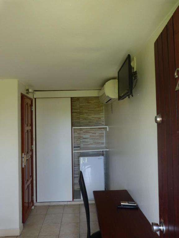 uma cozinha com um frigorífico e uma televisão na parede em Airport hotel em Ducos