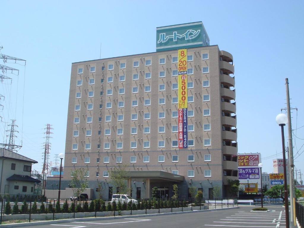 a hotel building with a sign on top of it at Hotel Route-Inn Ashikaga-2 in Ashikaga
