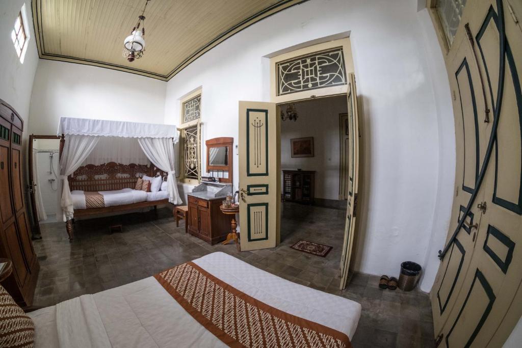 a room with a bedroom with a bed and a door at nDalem Natan Royal Heritage in Yogyakarta