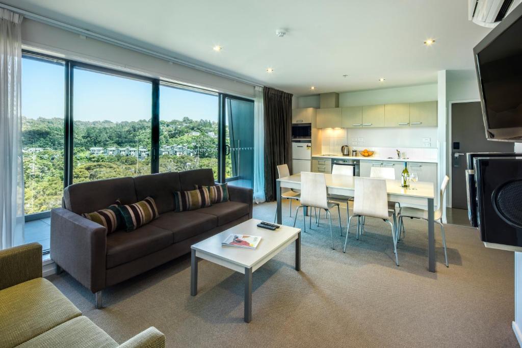 uma sala de estar com um sofá e uma mesa em Quest Albany Serviced Apartments em Auckland