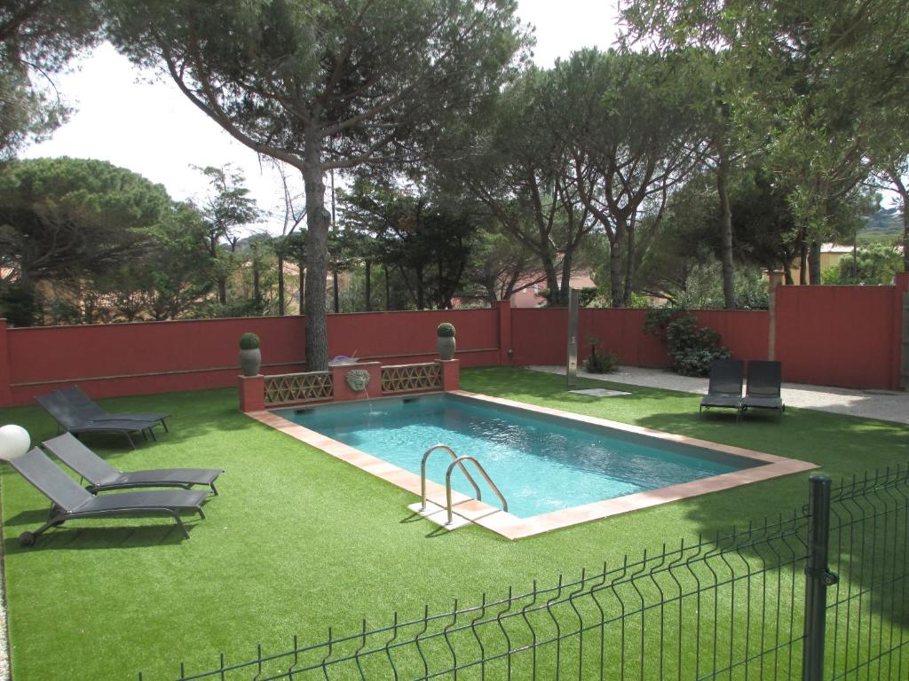 a swimming pool with green grass next to a fence at Villa Cote d'Asoet in Sainte-Maxime
