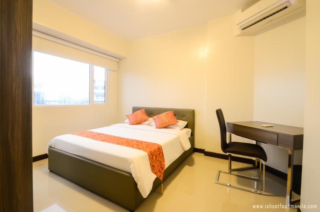Schlafzimmer mit einem Bett, einem Schreibtisch und einem Schreibtisch in der Unterkunft Extremeli Suites in Manila
