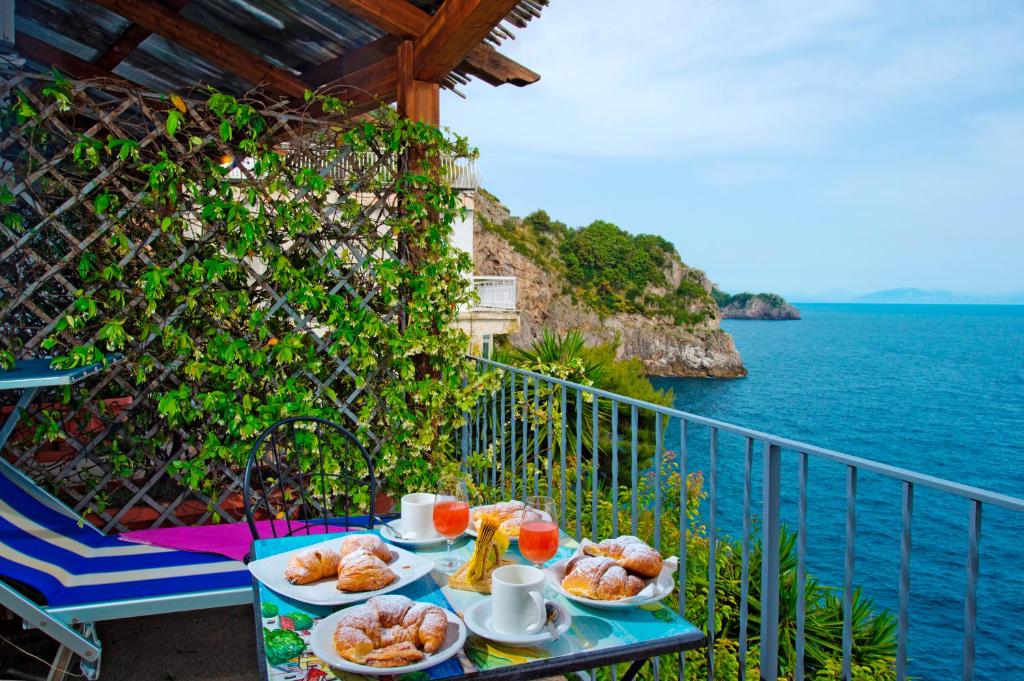 una mesa con platos de comida en un balcón con vistas al océano en Bed and Breakfast Da Claudio, en Conca dei Marini