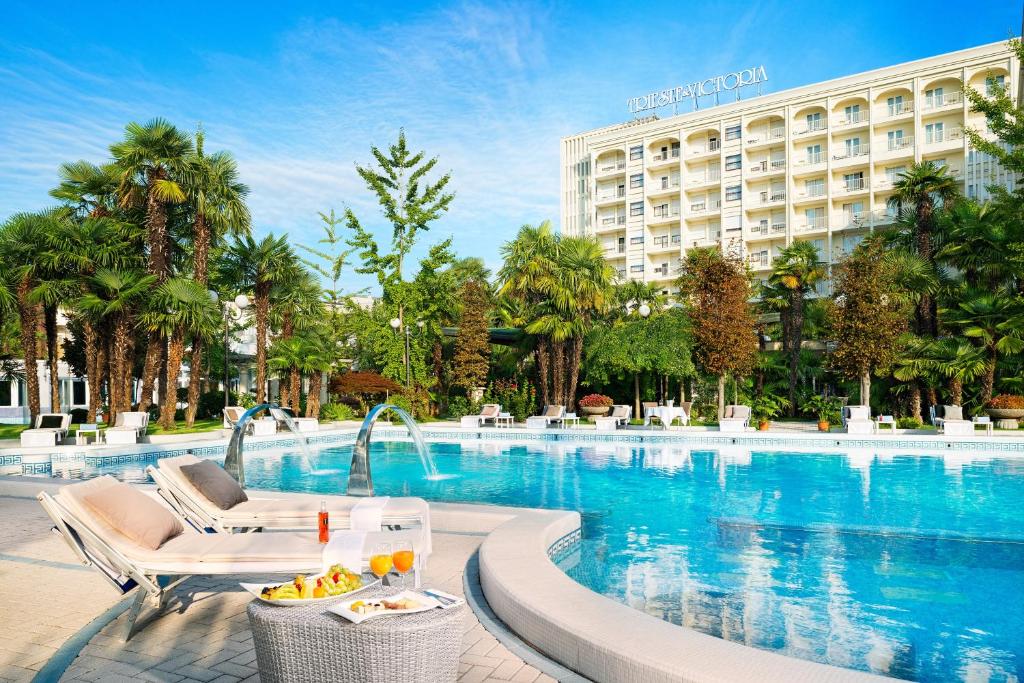 una piscina dell'hotel con un hotel sullo sfondo di Grand Hotel Trieste & Victoria ad Abano Terme