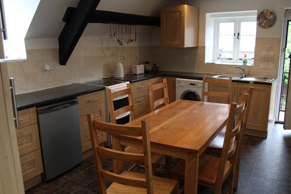 a kitchen with a wooden table and a table and chairs at Old Court Hotel & Apartments in Symonds Yat