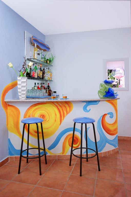 a kitchen with two bar stools and a colorful wall at Iris Hotel in Ischia