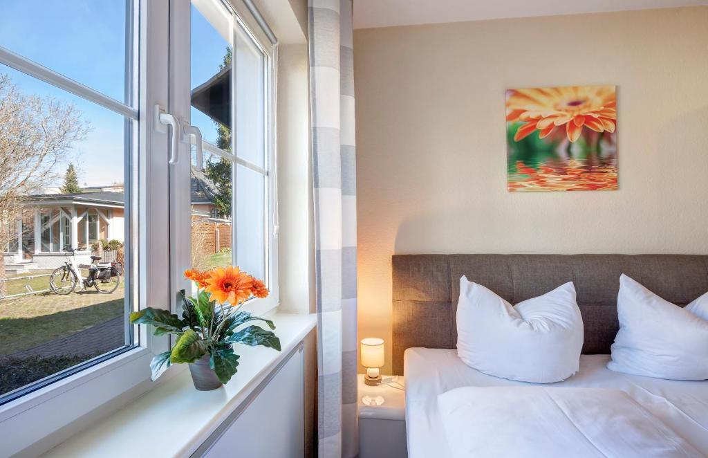 a bedroom with a bed and a window with a vase of flowers at Ferienwohnung Gunsilius in Zinnowitz