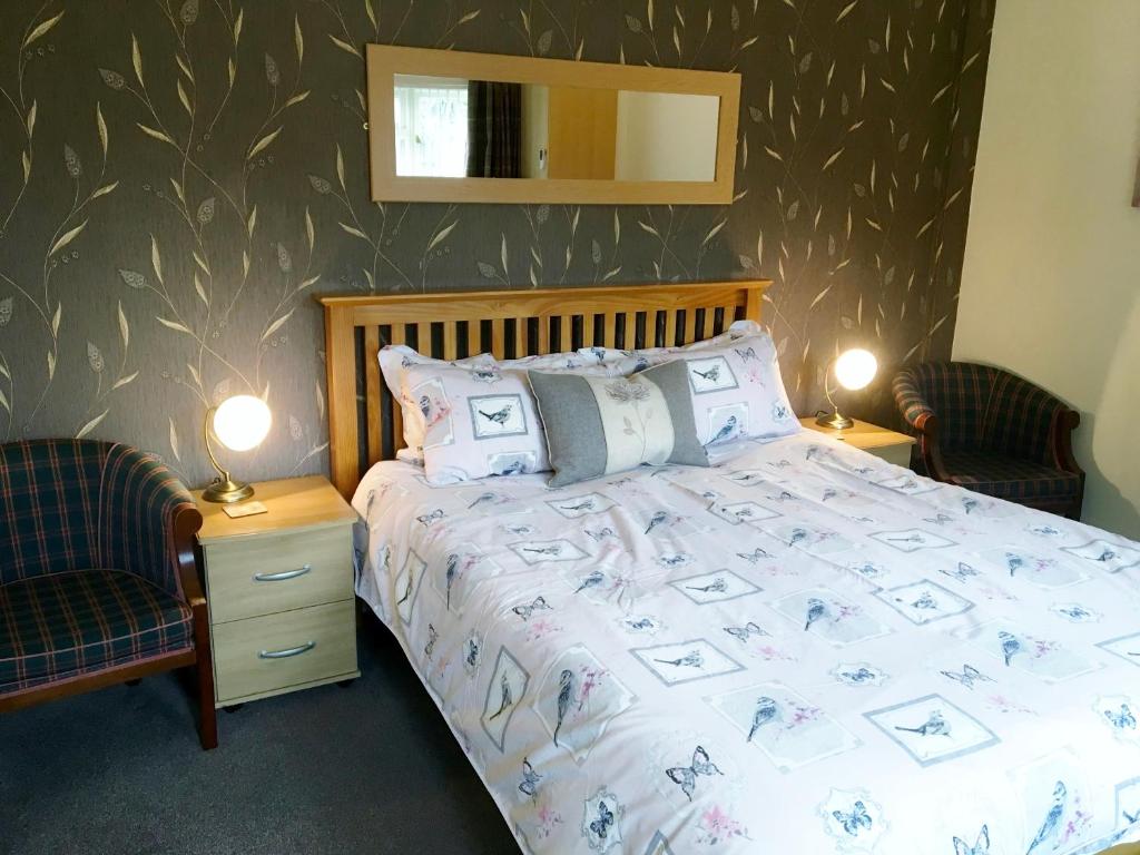 - une chambre avec un lit, deux chaises et un miroir dans l'établissement Ashleigh Lodge, à Hunstanton