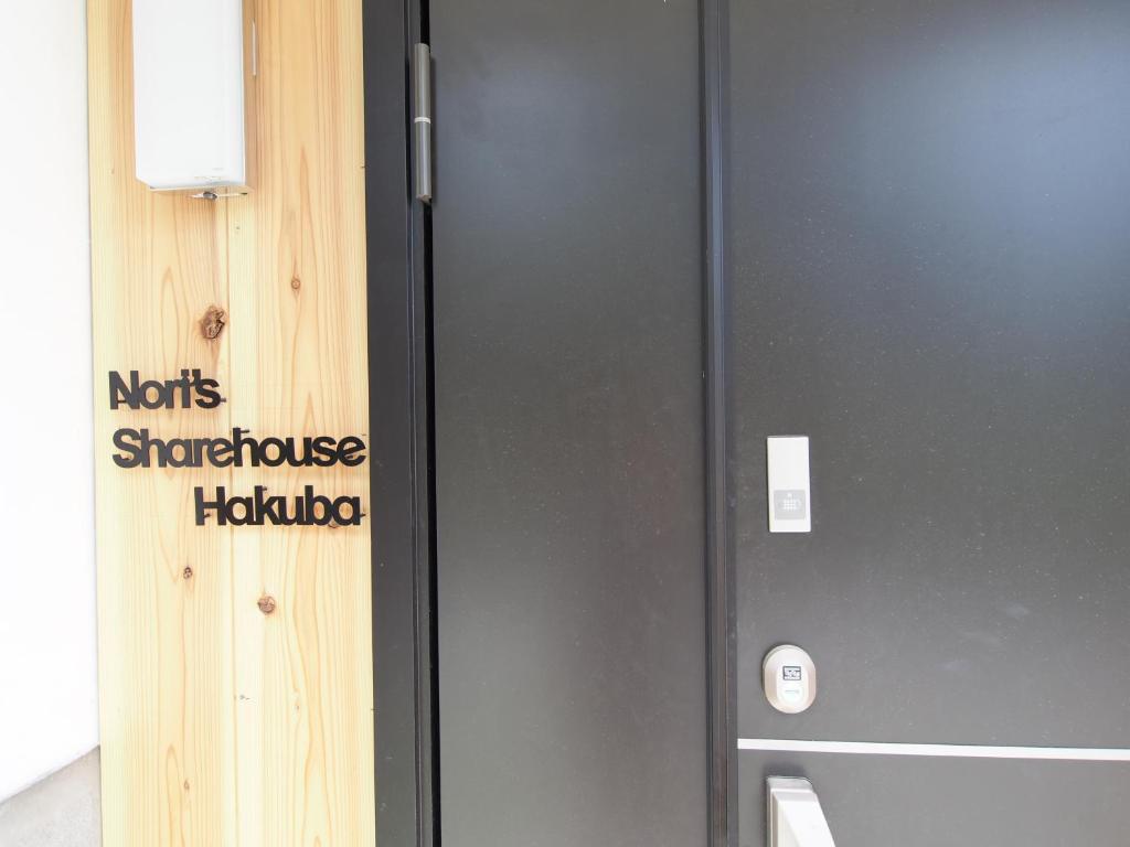 a metal door with a sign on the side of it at Nori's Sharehouse Hakuba in Hakuba