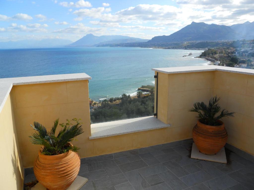 a balcony with two potted plants and a view of the ocean at Tenuta Sperlinga - Il Campanile in Santa Flavia