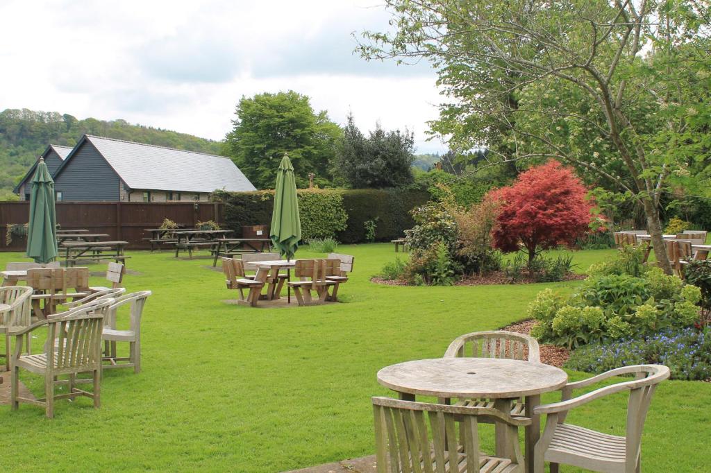 a garden with tables and chairs and umbrellas at Old Court Hotel & Apartments in Symonds Yat