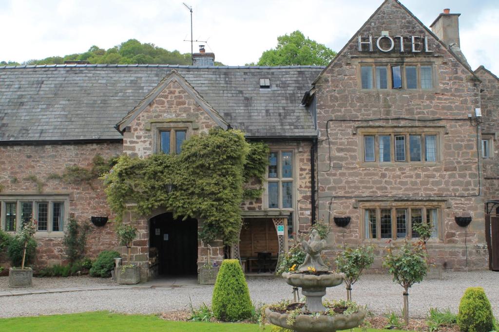an old stone hotel with a fountain in front of it at Old Court Hotel & Apartments in Symonds Yat