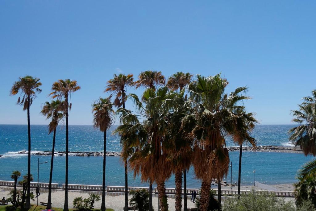 a row of palm trees on a beach with the ocean at Oneglia Coast Apt in Imperia