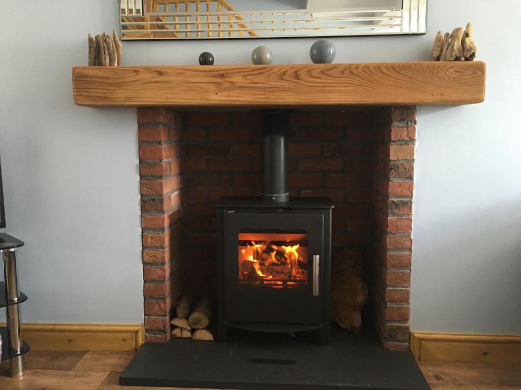 a brick fireplace with a fire in it at Waters Edge in Penclawdd