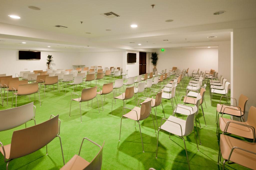 a room with chairs and tables and a green floor at Alimounda Mare Hotel in Karpathos