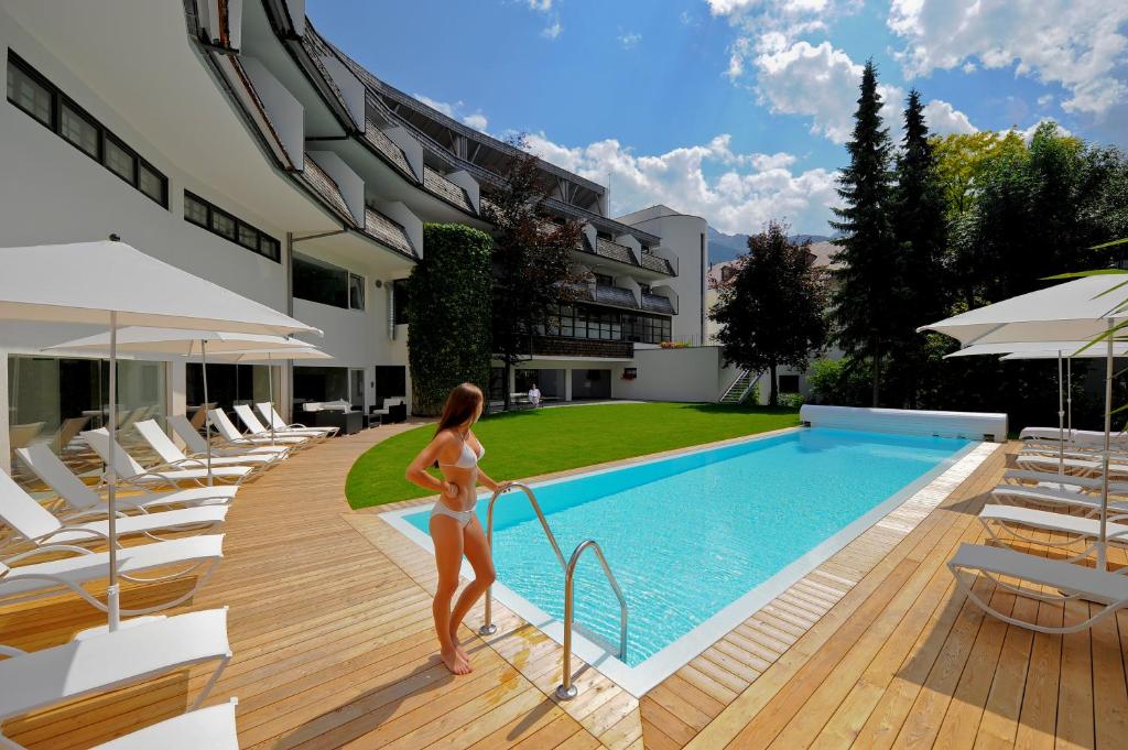 kobieta w bikini stojąca obok basenu w obiekcie Hotel Rauter w mieście Matrei in Osttirol