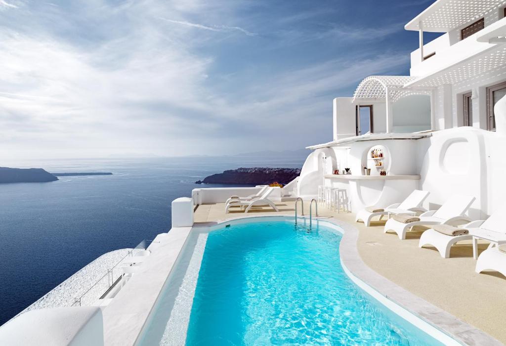 a pool on the side of a house with the ocean at Tholos Resort in Imerovigli