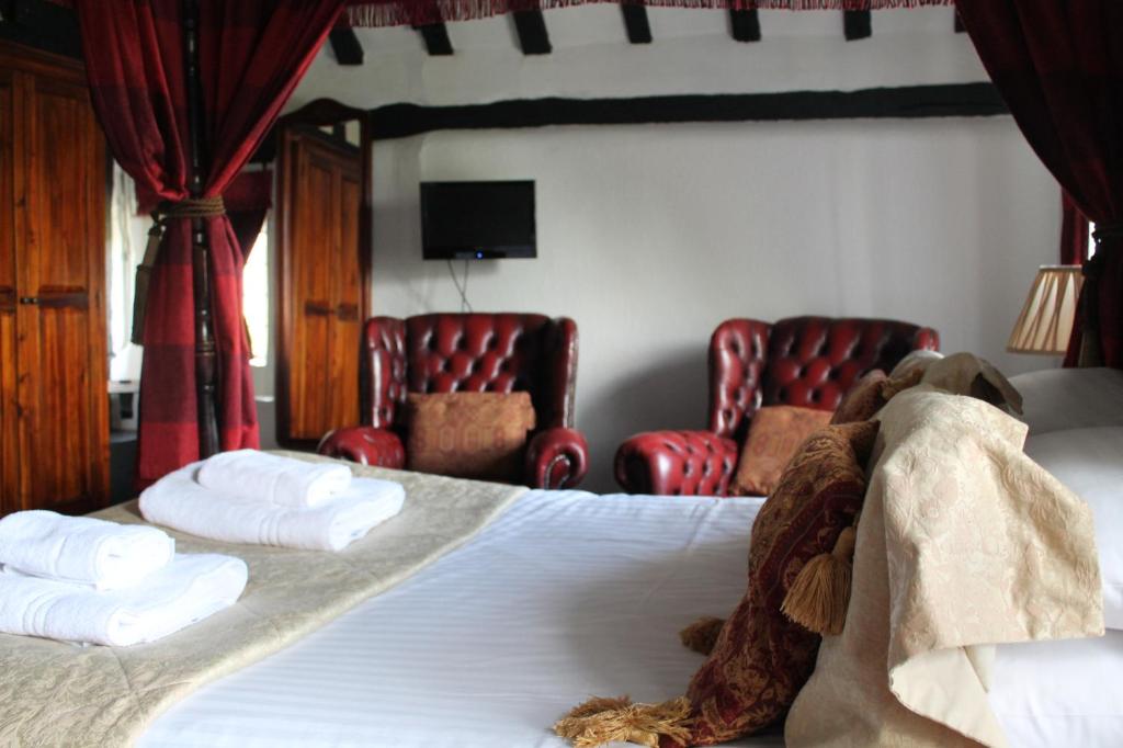a hotel room with a bed with red chairs at Old Court Hotel & Apartments in Symonds Yat