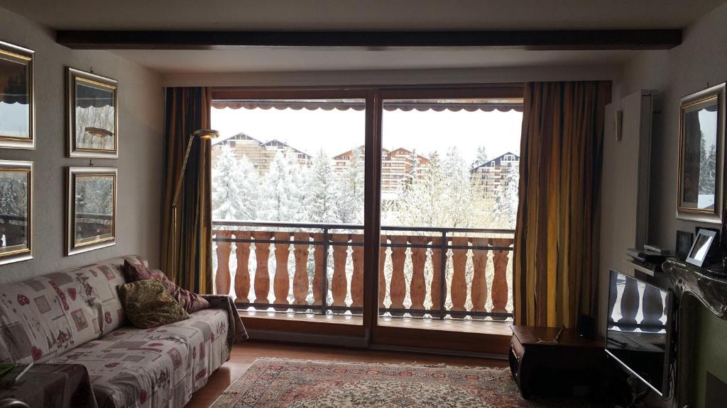 a living room with a couch and a large window at Apartment 24 Hotel Etrier pool & spa in Crans-Montana