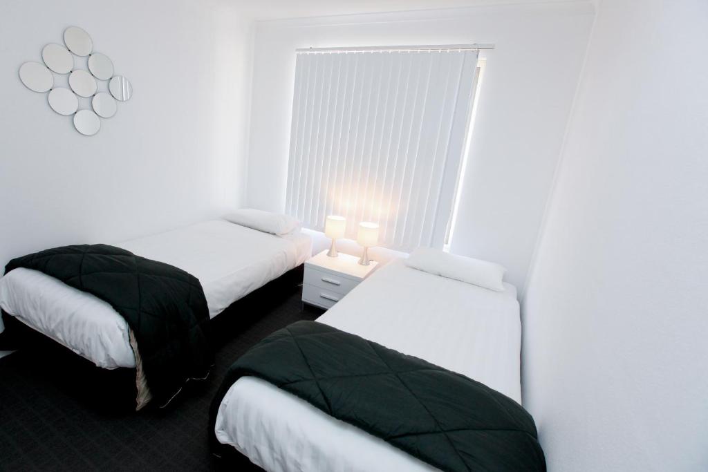 two beds in a room with white walls at 112 Olive Apartments in Mildura