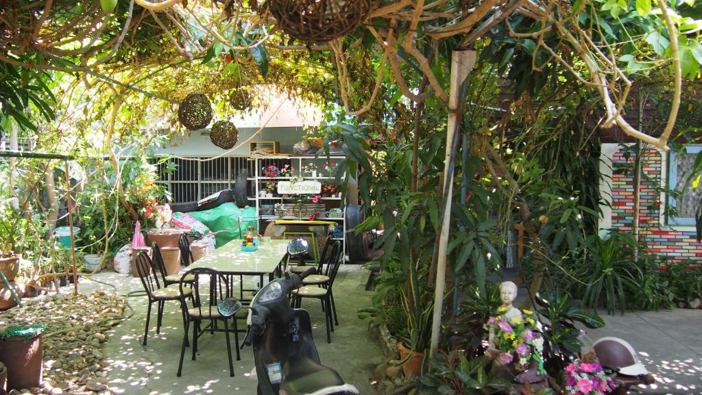 einen Garten mit einem Tisch, Stühlen und Pflanzen in der Unterkunft Baanchaokoh Homestay in Kanchanaburi