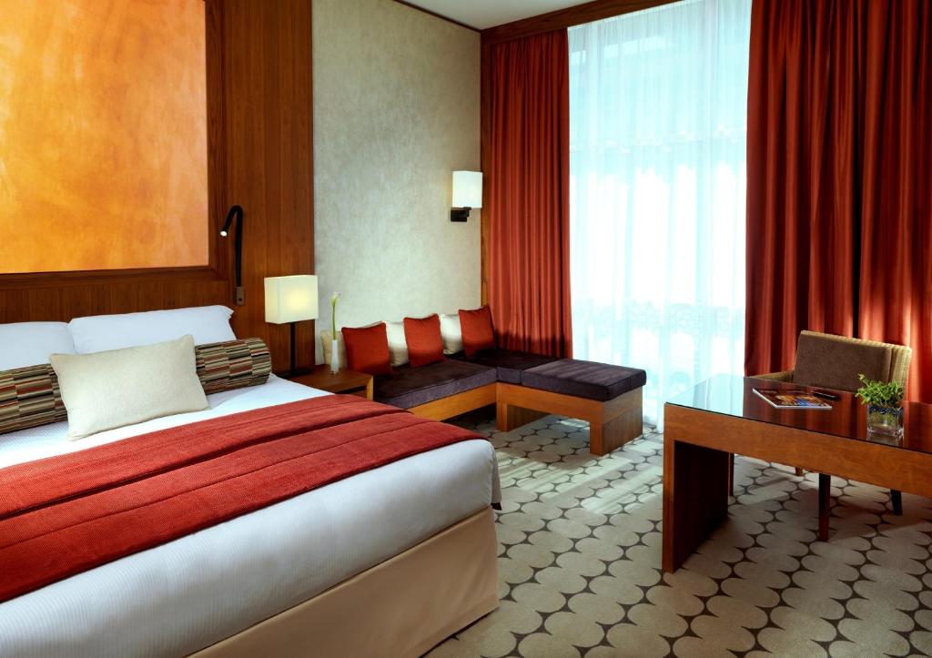 a hotel room with a bed and a desk and window at Yas Island Rotana Abu Dhabi in Abu Dhabi