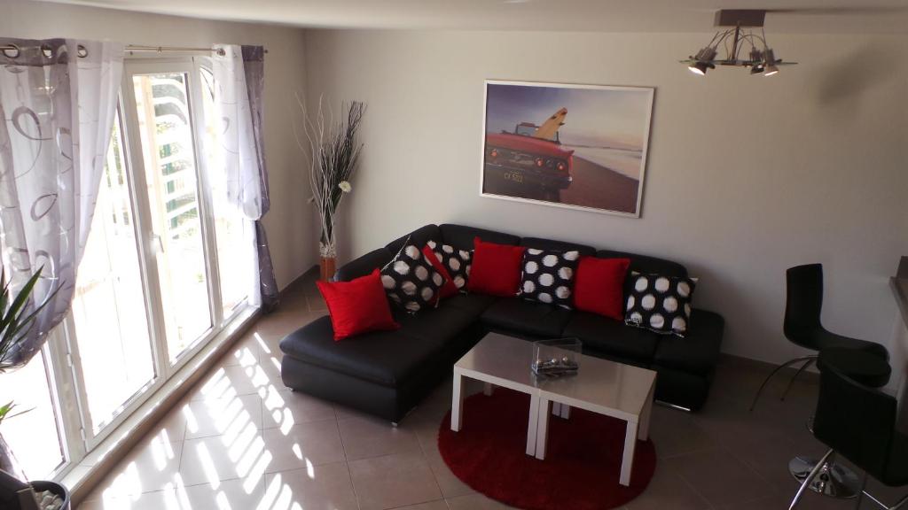 ラ・シオタにあるAppart Figuerolle Plageのリビングルーム(黒いソファ、赤い枕付)