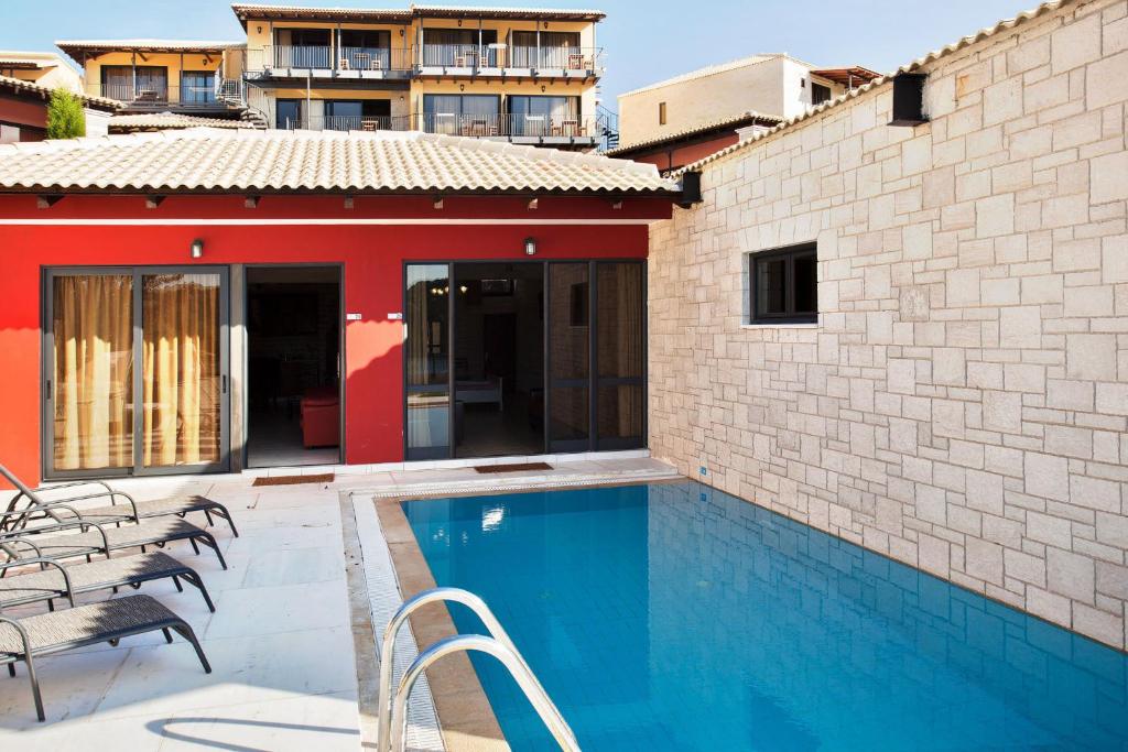 a house with a swimming pool next to a building at Ornella Beach Resort & Villas in Syvota