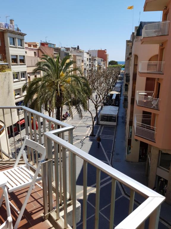 balcón con vistas a una calle con palmeras y edificios en Apartament a la Placeta de Sant Joan 21, 3r, en Sant Feliu de Guíxols