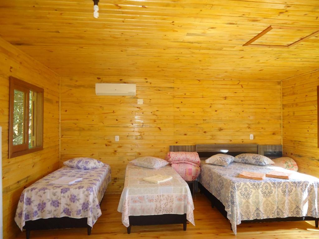 two beds in a room with wooden walls at Pousada do Belvedere - Sítio Ramos in Praia Grande