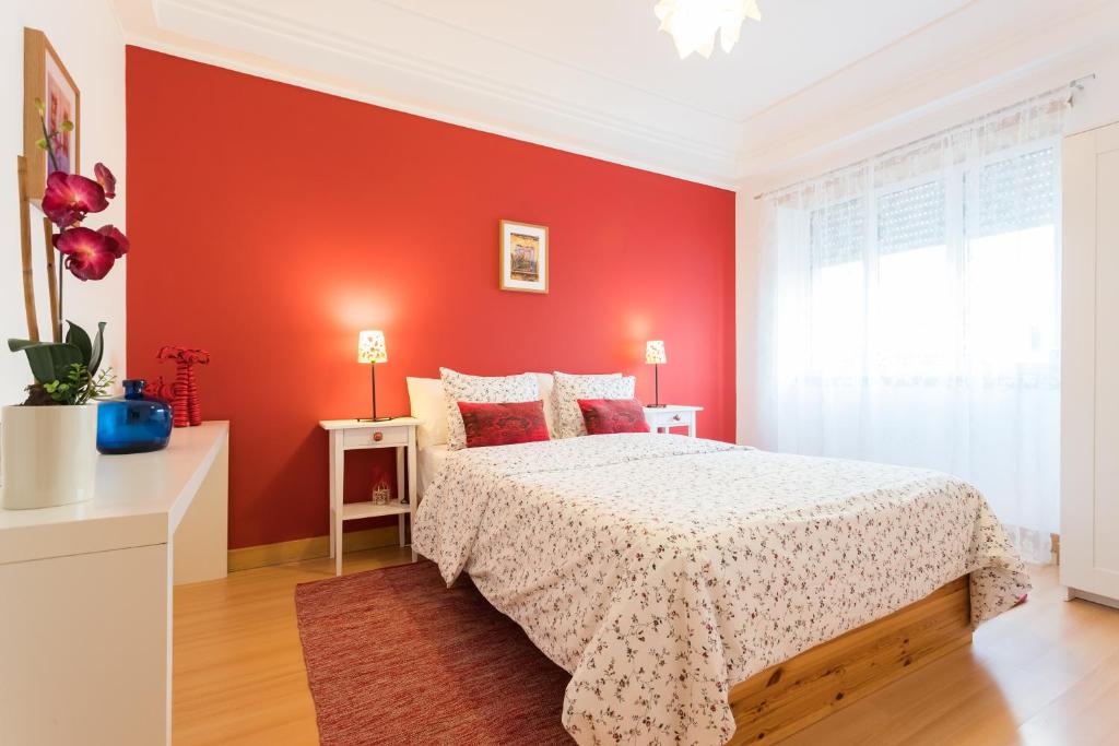 リスボンにあるTop Location Beautiful Apartmentの赤い壁のベッドルーム1室、ベッド1台が備わります。