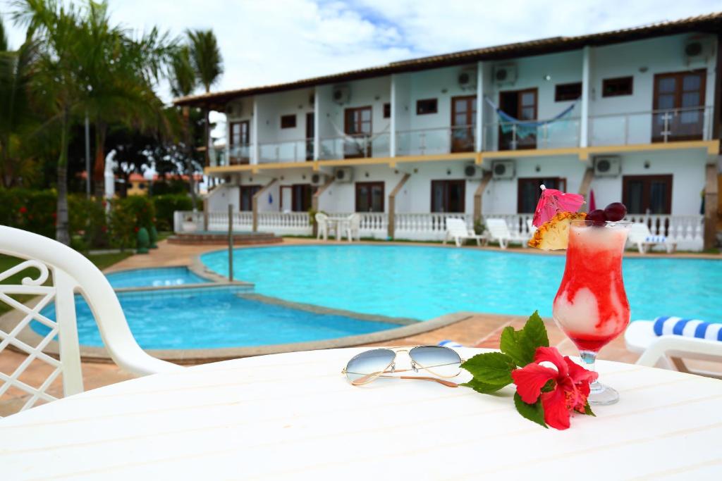 a table with glasses and a vase on it next to a pool at Benko´s Praia Hotel in Porto Seguro