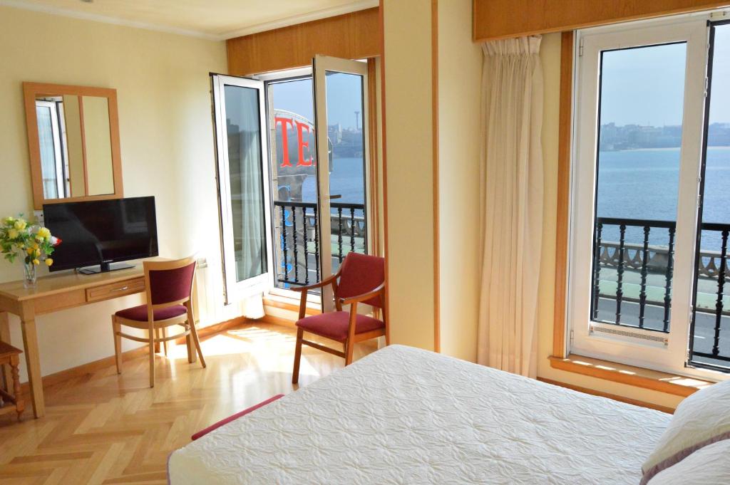ア・コルーニャにあるホテル クリスタル 2のベッド、デスク、窓が備わるホテルルームです。