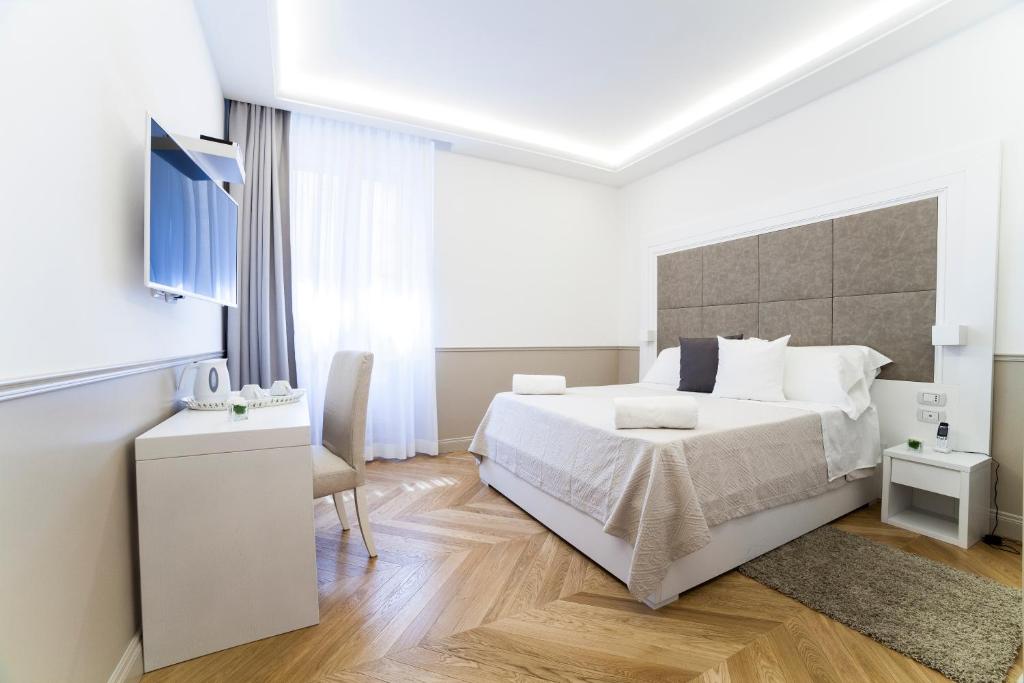 biała sypialnia z łóżkiem i telewizorem w obiekcie Margherita Suites w Rzymie