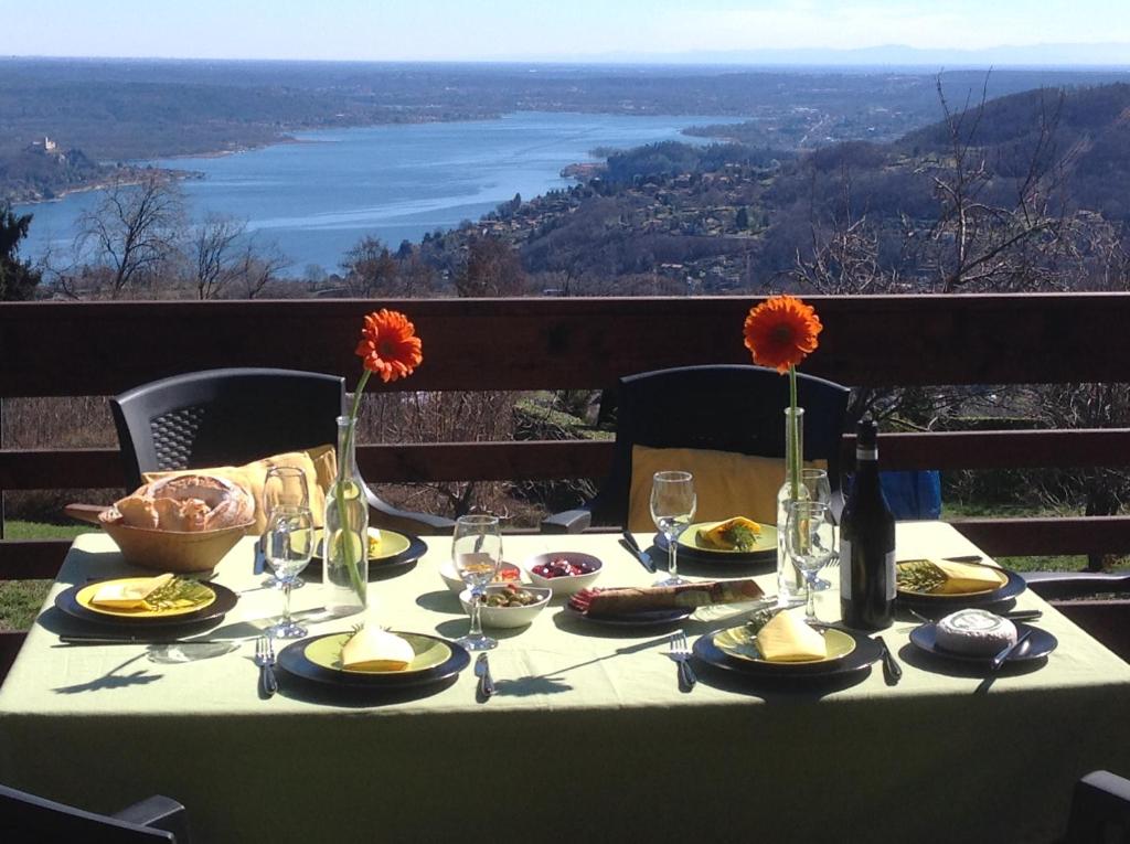 einen Tisch mit Teller mit Lebensmitteln und Blumen darauf in der Unterkunft Gardenpark Soleil in Nebbiuno