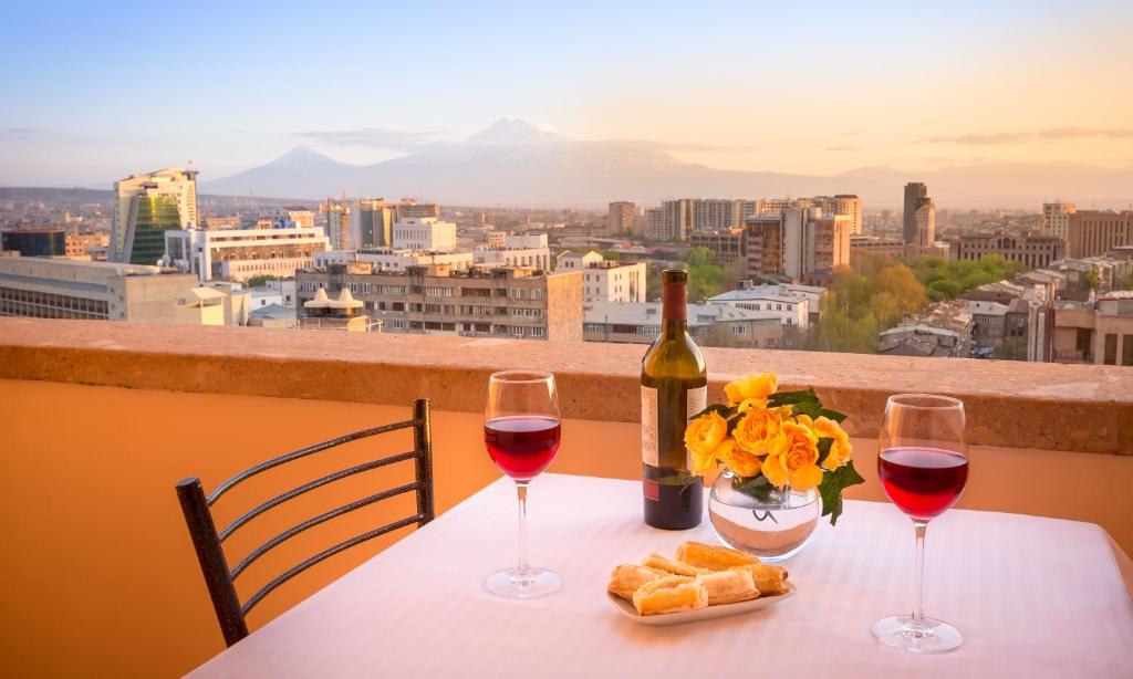 una mesa con dos copas de vino, pan y flores en 14 Floor Hotel, en Ereván