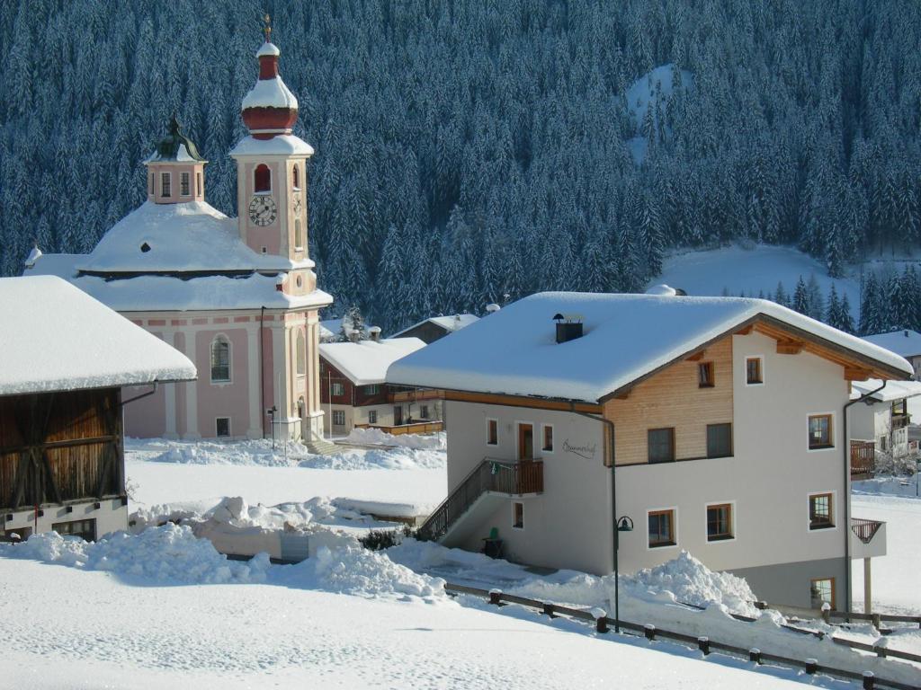 a town covered in snow with a clock tower at Brunnerhof in Strassen