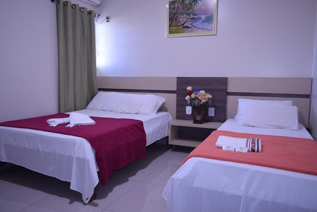 two beds in a hotel room with towels on them at Hotel Sul Real in Ji-Paraná