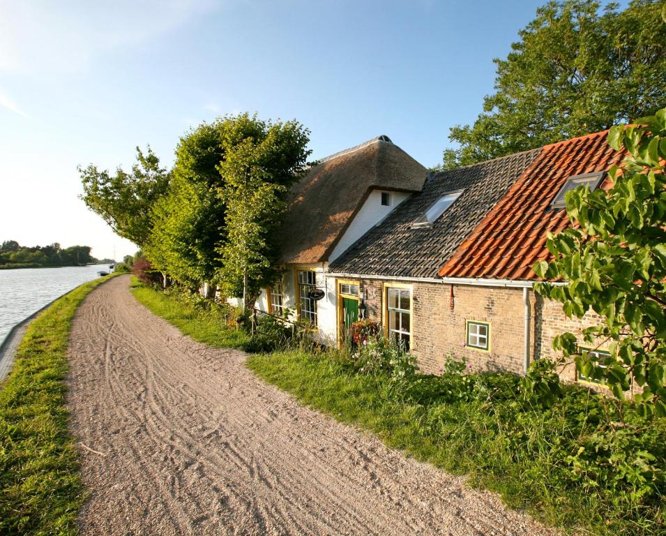 ein Haus an der Seite einer Straße neben einem Fluss in der Unterkunft B&B Rechthuis van Zouteveen in Schipluiden