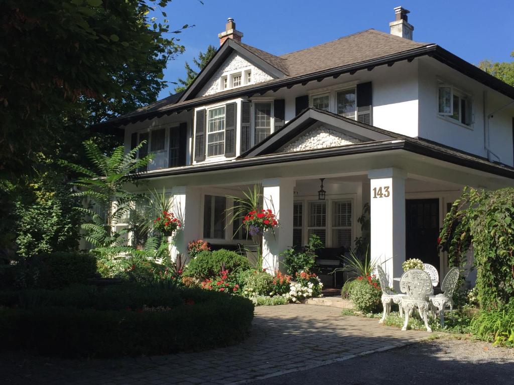 a white house with two white chairs on a driveway at Bernard Gray Hall Bed and Breakfast in Niagara on the Lake