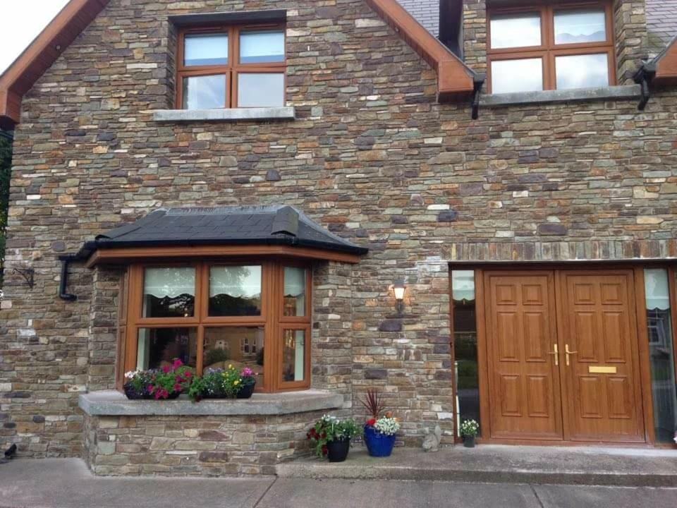 a brick house with a wooden door and windows at Beechwood Lodge in Blarney