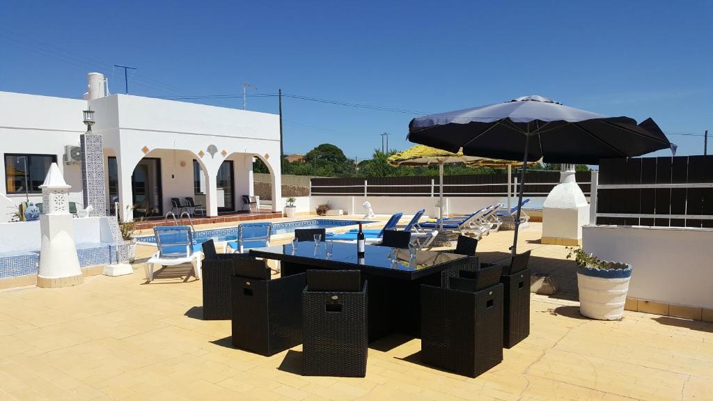 uma mesa com um guarda-chuva ao lado de uma piscina em Villa V4 Filomena em Mosqueira