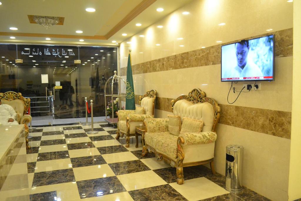 鋁巴哈的住宿－Manazel Al Faisal Furnished Apartments，一间设有椅子和平面电视的等候室