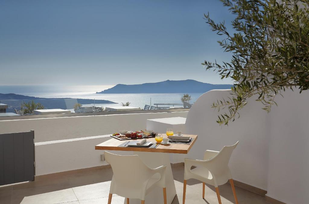 uma mesa e cadeiras com vista para o oceano em Callia Caves - Adults Only em Fira