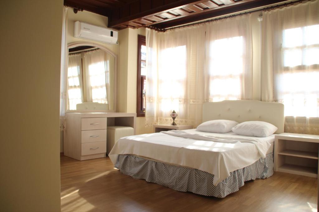 a bedroom with a bed with white sheets and windows at Munchen Pension in Antalya