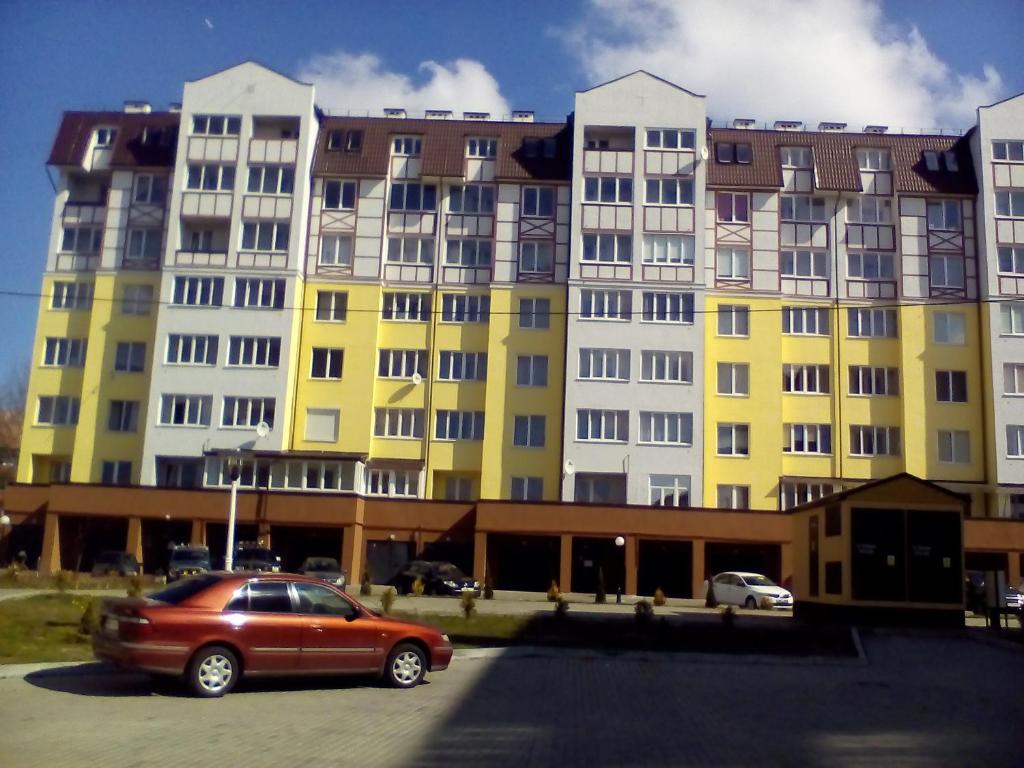 スヴェトロゴルスクにあるApartment Yablonevaya 5の黄色い建物の前に停車した赤い車