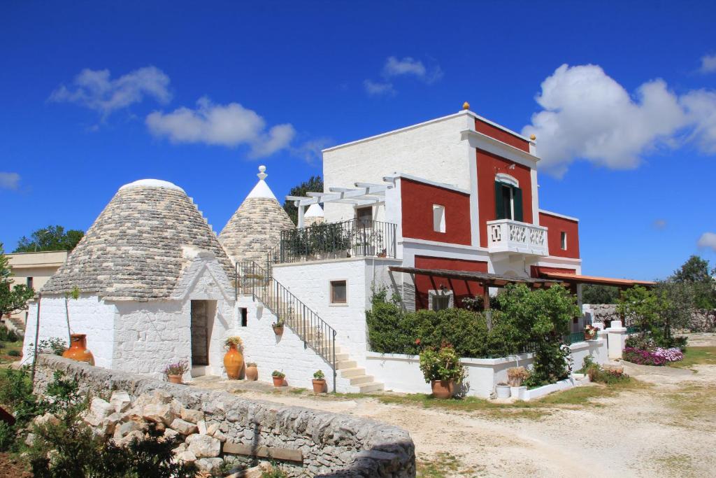 a large white building with a staircase in front of it at Masseria Trulli sull'Aia in Cisternino