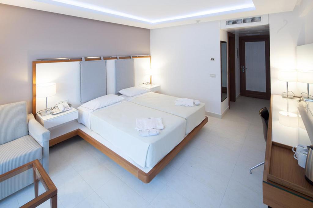 a bedroom with a large white bed and a couch at Alimounda Mare Hotel in Karpathos