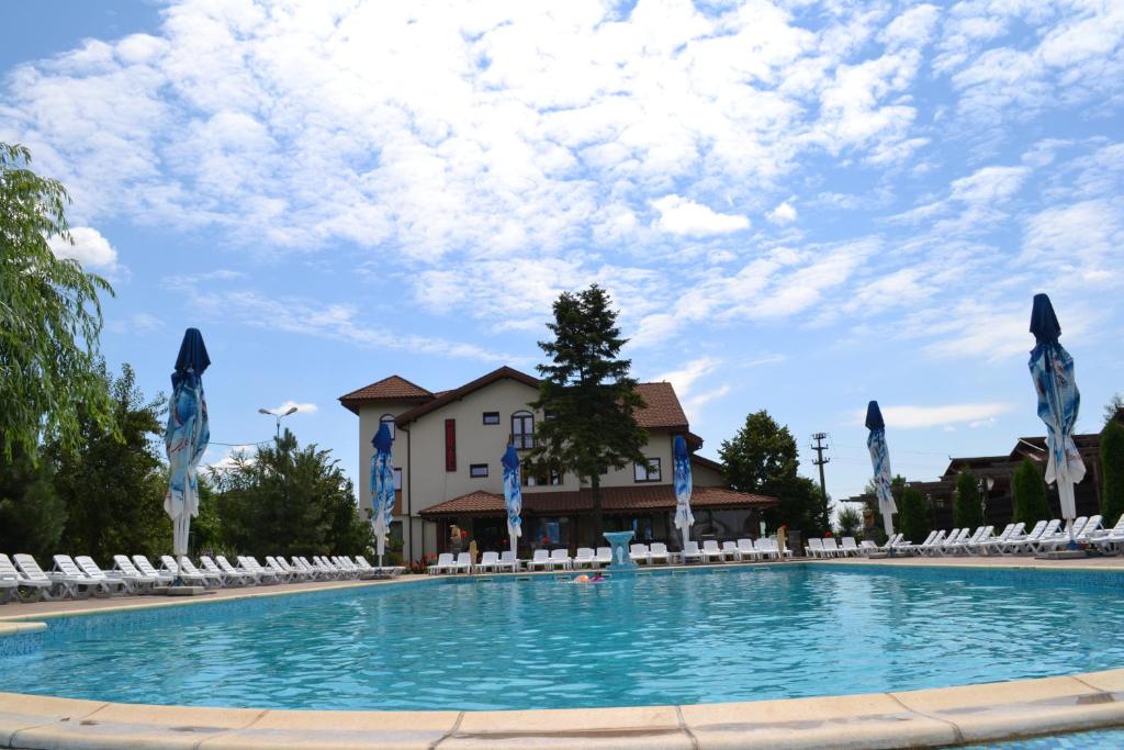 a large swimming pool with chairs and a building at Hotel Doi Taurasi in Afumaţi