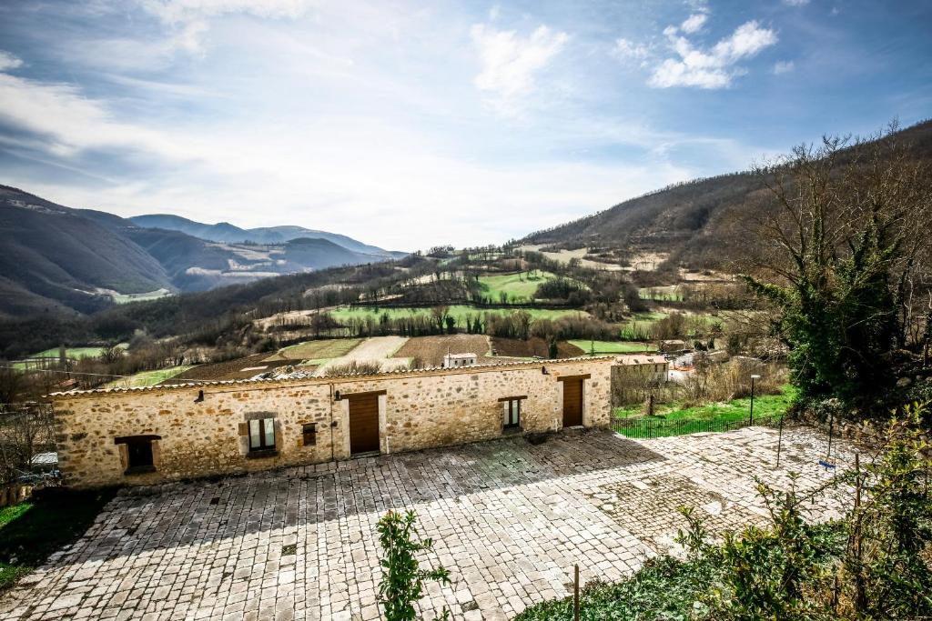 SellanoにあるLe Aie Di Postignanoの山を背景にした古い石造りの建物